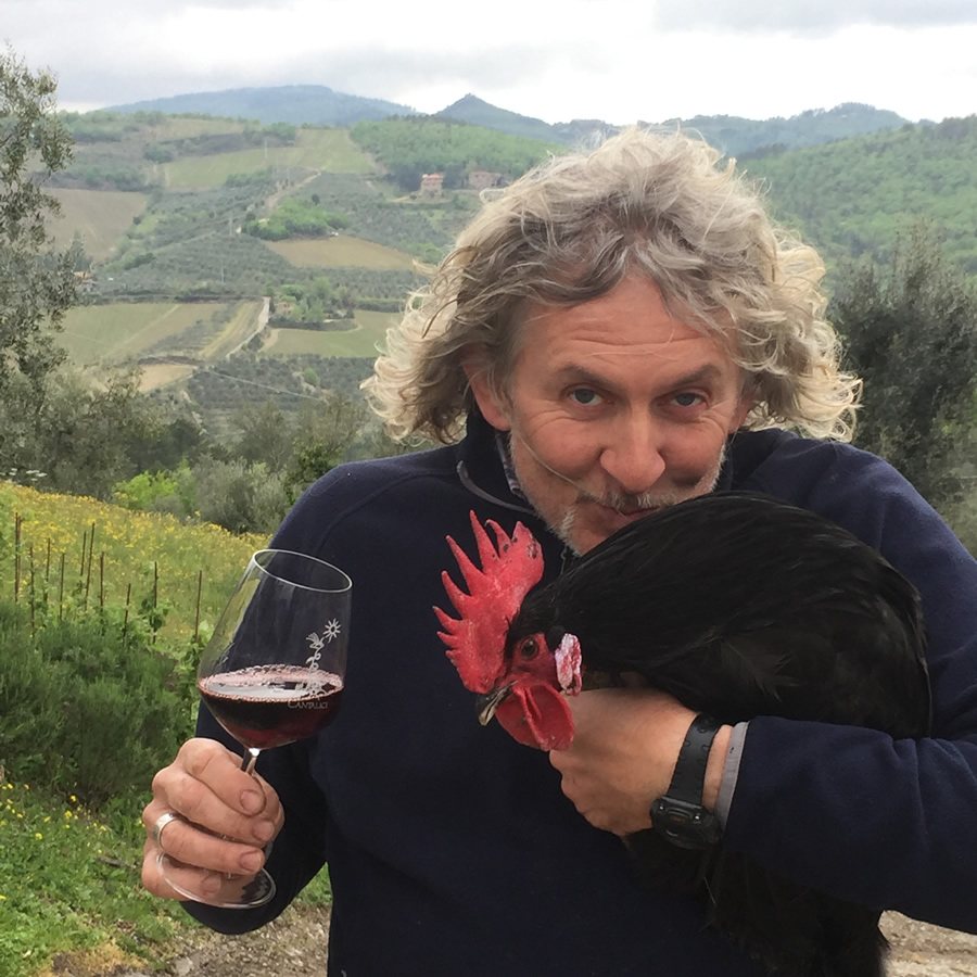 Carlo Cantalici con un bicchiere di vino Chianti Classico e un gallo nero, simbolo di questa zona in braccio